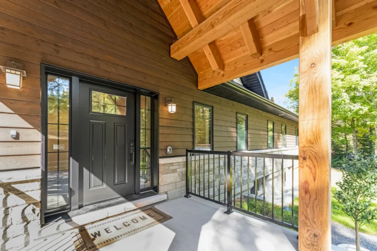 Black front door with a welcome mat on a wooden porch