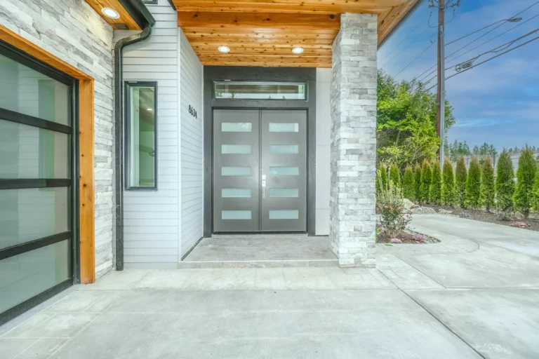 Grey wooden front door beside green plants