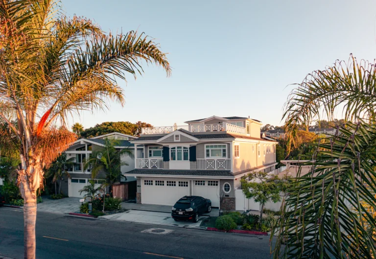 White two-story house exterior framed by green trees